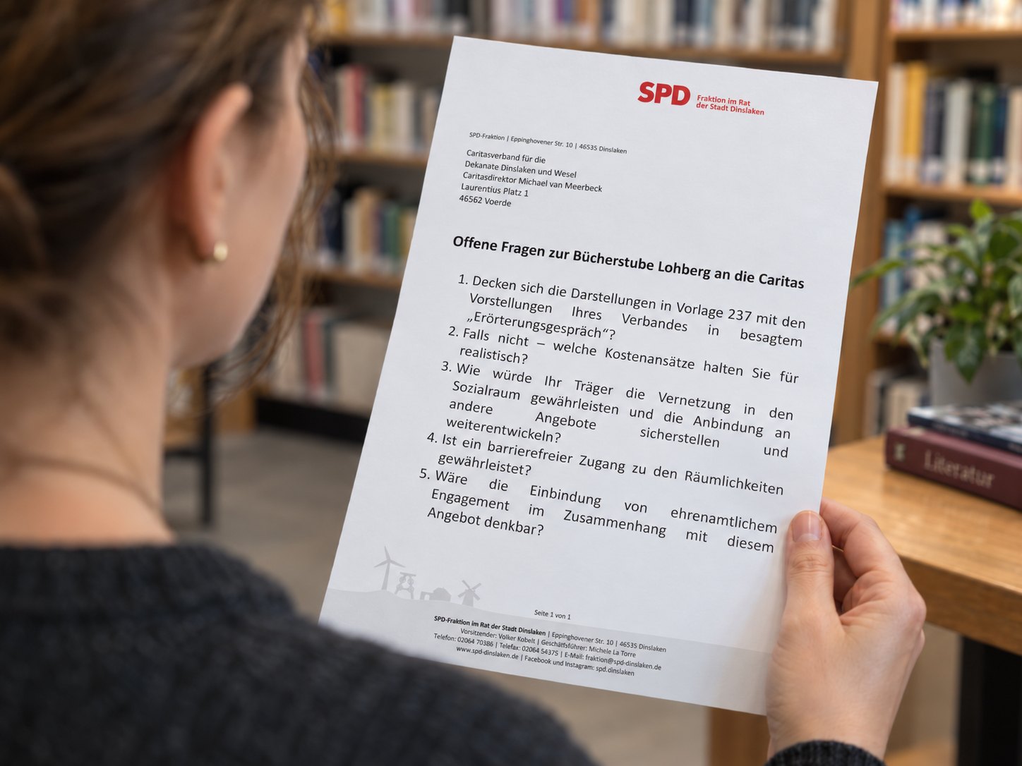 Blick mit Fokus auf einen Brief, der von einer weiblichen Person in einer Bibliothek gelesen wird
